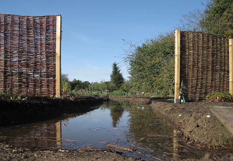 Ausgekofferte Wege, die später mit
groben Holzhäckseln aufgefüllt wurden.
Auf diesem Wege kann Wasser bei
Starkregenereignissen von den höher
gelegenen Beeten abfließen. Ausgekofferte Wege, die später mit
groben Holzhäckseln aufgefüllt wurden.
Auf diesem Wege kann Wasser bei
Starkregenereignissen von den höher
gelegenen Beeten abfließen.